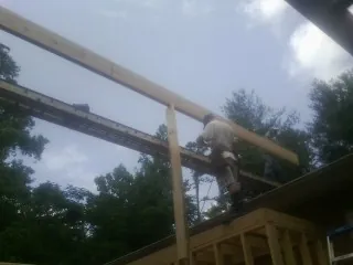 Carpenter setting a ridge beam over a new addition frame — Ice Dam Removal by Roofing Brothers in Taftville