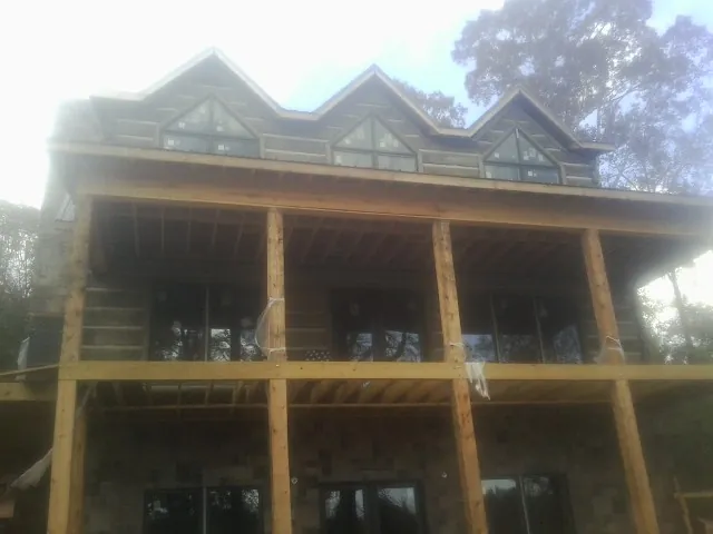 Dormers and porch framing on a large log home under construction — Roof Coating work by our crew in Taftville