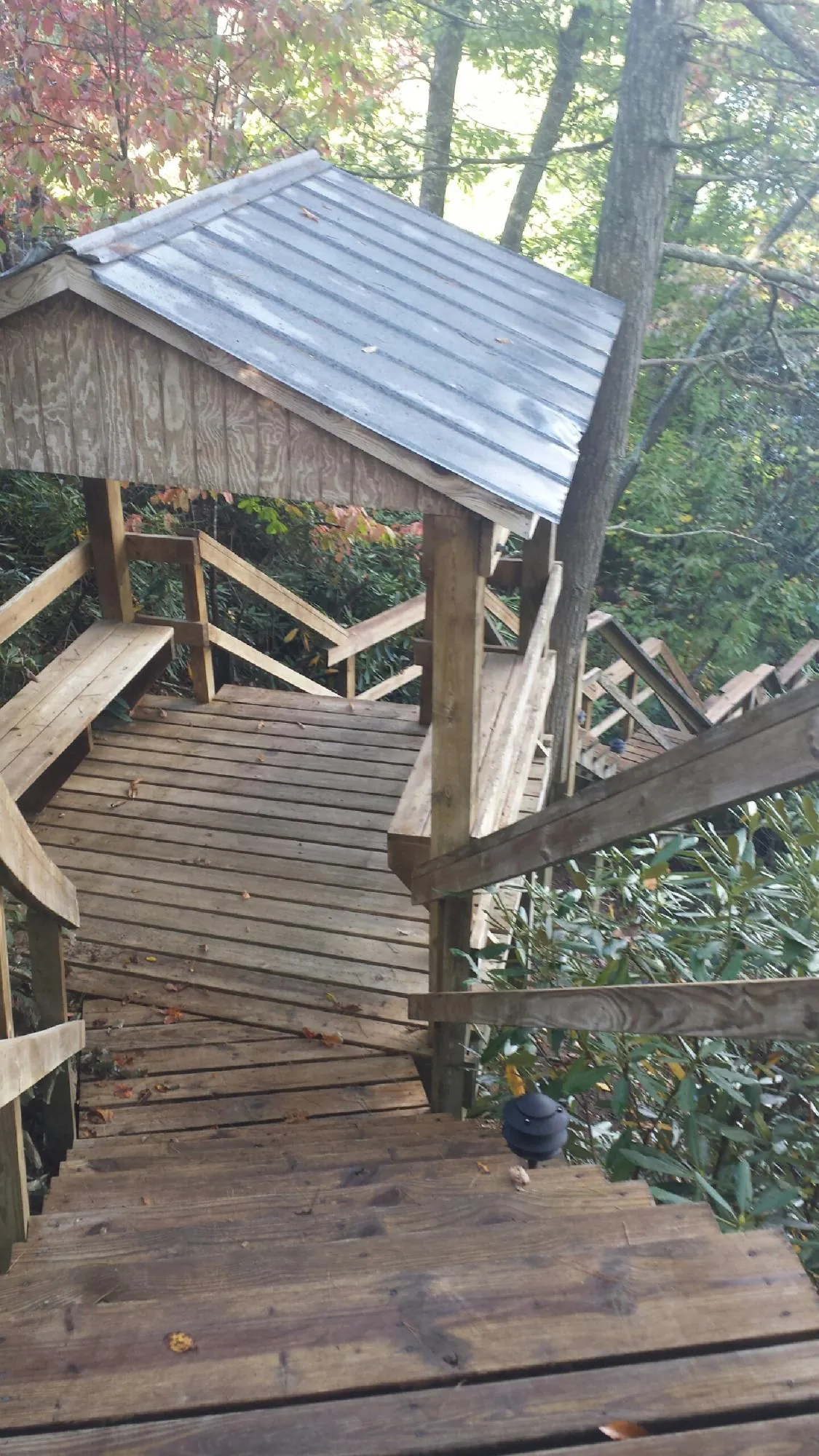 Metal roofed shelter over wooden steps on a wooded walkway — Skylight Repair & Installation work by our crew in Taftville