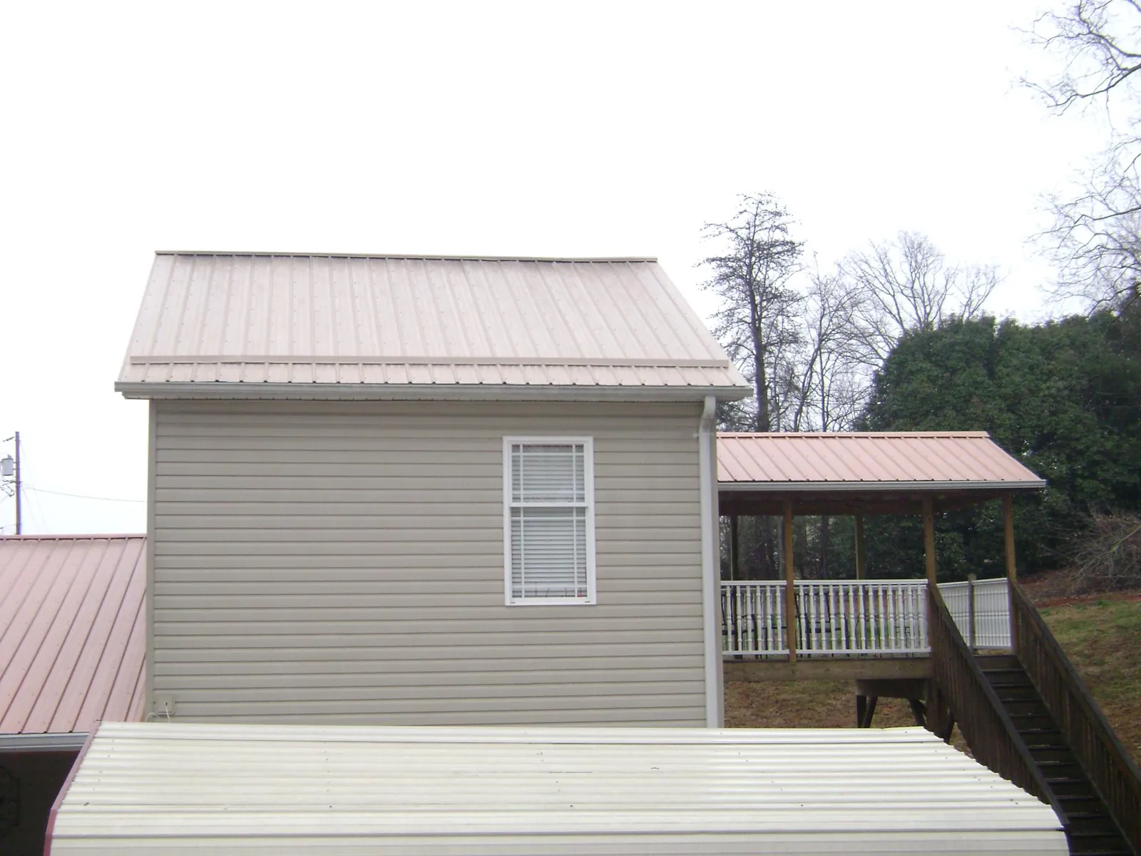 Tan metal roofs on a two story addition and attached porch, from a Roof Replacement job in Taftville