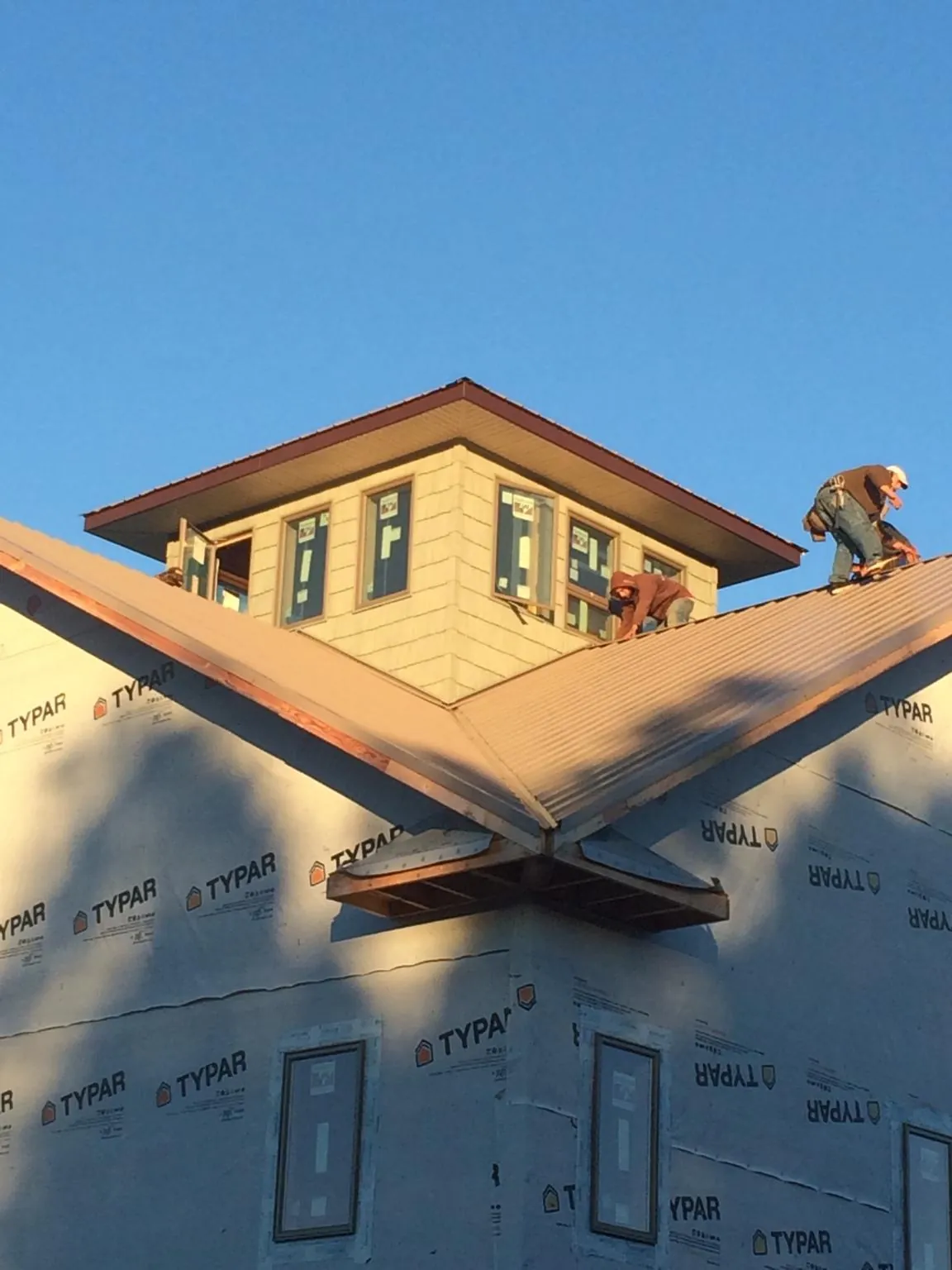 Roofers working around a rooftop cupola on a new metal roof at sunset — Roof Waterproofing in Taftville by Roofing Brothers